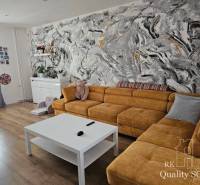 Wohnzimmer in einem Einfamilienhaus mit gelbem Sofa und abstrakter Wand mit bunten Pinselstrichen.