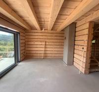 Interieur einer Holzhütte mit großem Fenster und Treppe.