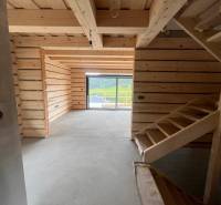 Eine Hütte mit einem hölzernen Interieur, einer Treppe und einem verglasten Ausblick auf die umliegende Natur.