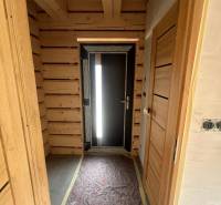 Holzflur in einer Hütte mit dunklen Türen und einer freiliegenden Glühbirne an der Decke.
