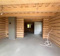 Holzinterieur der Hütte mit Betonboden und unfertigen Elementen.