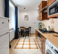 Eine Küche mit rotbraunen Schränken, einem Esstisch und einem Herd in einer Zweizimmerwohnung.