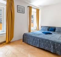 Helles Schlafzimmer mit Doppelbett und großen Fenstern in einer 2-Zimmer-Wohnung.