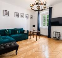 Wohnzimmer in einer Zweizimmerwohnung mit Sofa, Holzboden und Fernseher.