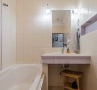 Badezimmer in einer 2-Zimmer-Wohnung mit Badewanne und Waschbecken mit lila Fliesen.