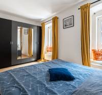 Schlafzimmer mit großem Schrank, Bett und gelben Vorhängen in einer 2-Zimmer-Wohnung.