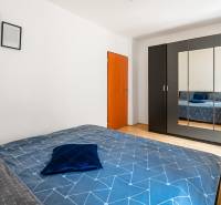 Schlafzimmer in einer Zweizimmerwohnung mit einem großen Schrank und blauer Bettwäsche.