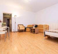 Einzimmerwohnung mit Holzboden, gelbem Sofa, Tisch und Bett.