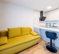 Einzimmerwohnung mit Sofa, Küchenzeile und Bartisch in neutraler Farbpalette.