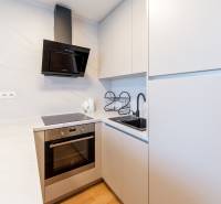 Eine Küche in einem Studio-Apartment mit weißen Schränken und eingebauten Geräten.