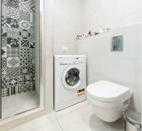Badezimmer in einem Studio-Apartment mit Waschmaschine, Dusche und Toilette, Fliesen mit Ornamenten.