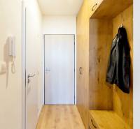 Im Flur des Einzimmerapartments mit Holzmöbeln hängt eine schwarze Jacke an der Garderobe.