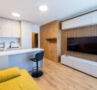 Einzimmerwohnung mit modernem Küchenbereich, gelbem Sofa und holzverkleideter Wand.
