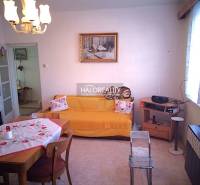 Wohnzimmer eines Einfamilienhauses mit Esstisch, Sofa und Radio auf dem Regal.