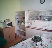 Innenraum eines Einfamilienhauses mit Retro-Möbeln, Mikrowelle und einem Esstisch mit geblümter Tischdecke.