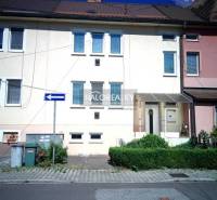 Ein Einfamilienhaus in Nováky mit weißer Fassade, grünen Sträuchern und einem Parkplatz vor dem Haus.