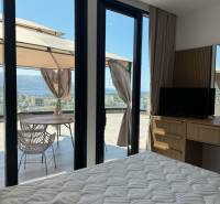 Innenraum einer Ferienwohnung mit Bett, Schrank und Terrasse mit Meerblick.