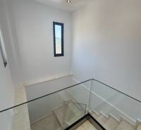 Treppe in einer Ferienwohnung mit großem Glasgeländer und schmalem Fenster.