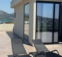 Terrasse einer Ferienwohnung in Ksamil mit Blick auf die Berge und zwei Liegestühlen.
