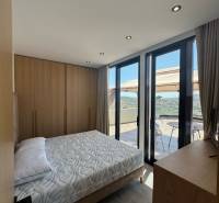 Schlafzimmer in einer Ferienwohnung mit Balkonblick, Holzmöbeln und Bett.