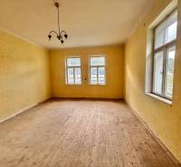 Ein Zimmer in einem Einfamilienhaus mit Holzboden, gelben Wänden und einer Hängelampe.