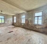 Ein verlassenes Zimmer in einem Einfamilienhaus mit beschädigten Böden und Wänden.