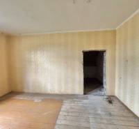 Ein Zimmer in einem Einfamilienhaus mit Holzboden und beigen Tapeten.