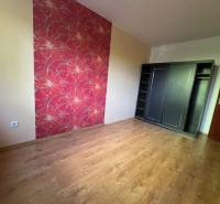 Ein Zimmer mit Holzboden und Blumenmuster-Tapete in einer 3-Zimmer-Wohnung.