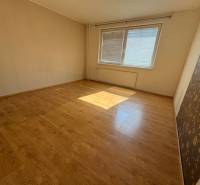 Ein Zimmer mit hellem Laminatboden und zwei Fenstern in einer 3-Zimmer-Wohnung.