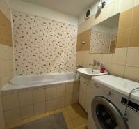 Badezimmer in einer 3-Zimmer-Wohnung mit Badewanne, Waschmaschine und Fliesen an den Wänden.