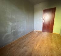 Ein Raum mit Holzboden und grauen Wänden in einer 3-Zimmer-Wohnung.