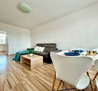 Wohnzimmer in einer 4-Zimmer-Wohnung mit Sofa und Esstisch mit Stühlen.