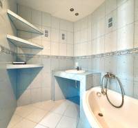 Ein Badezimmer mit hellblauen Fliesen, einer Badewanne und einem Waschbecken in einer 4-Zimmer-Wohnung.