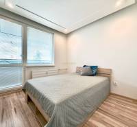 Helles Schlafzimmer in einer 4-Zimmer-Wohnung mit Laminatboden und einfachem Bett.
