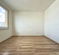 Ein leerer, heller Raum mit Holzboden in einer Vierzimmerwohnung.