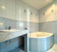 Ein Badezimmer mit hellblauen Fliesen und einer Eckbadewanne in einer Vierzimmerwohnung.