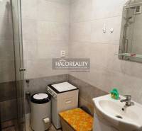 Badezimmer mit Waschbecken, Dusche und Waschmaschine in einer 2-Zimmer-Wohnung.