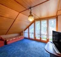Ein gemütlicher Raum in einer Hütte mit einem Sessel, einem Sofa, einem Fernseher und großen Fenstern mit Aussicht.