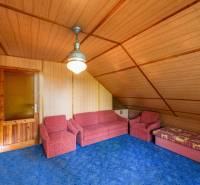 Holzinterieur der Hütte mit Sitzgarnitur und blauem Teppich.