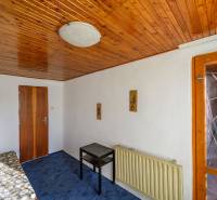 Holzdecke, Bett, Tisch, blauer Teppich, Lampe an der Wand in der Hütte.