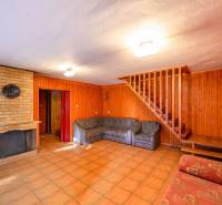 Das Innere der Hütte mit einem gemauerten Kamin, Holzverkleidungen und einer Treppe.