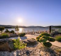 Der Garten am Wasser in Ružiná mit Blick auf den See und Liegestühlen bei Sonnenuntergang.