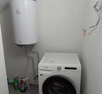 Waschküche in einer 2-Zimmer-Wohnung mit Waschmaschine und Boiler.