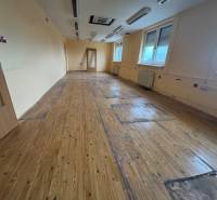 Zu vermietender Raum in einem Gebäude mit Holzboden, angeboten von einem Immobilienbüro.