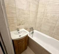 Badezimmer in einer 2-Zimmer-Wohnung mit Badewanne und Waschbecken in Holzdekor.