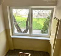 Flur mit Treppe und Fenster im Gebäude, draußen Grünfläche. Bietet eine 2-Zimmer-Wohnung an.