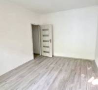 Ein leerer Raum mit Laminatboden in einer 2-Zimmer-Wohnung, neutrale Wände und eine Deckenleuchte.