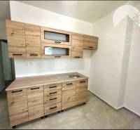 Küche in einer 2-Zimmer-Wohnung mit einem Holzschrank und Keramikboden.