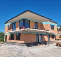 Der Außenbereich einer im Bau befindlichen 3-Zimmer-Wohnung in Dubová mit Ziegelwänden und großen Fenstern.