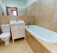 Badezimmer in einem Einfamilienhaus mit Badewanne, Waschbecken und WC, umgeben von Keramikfliesen.